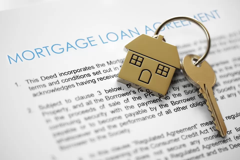 Close-up on mortgage application terms and house-shaped gold keychain with gold key on it.